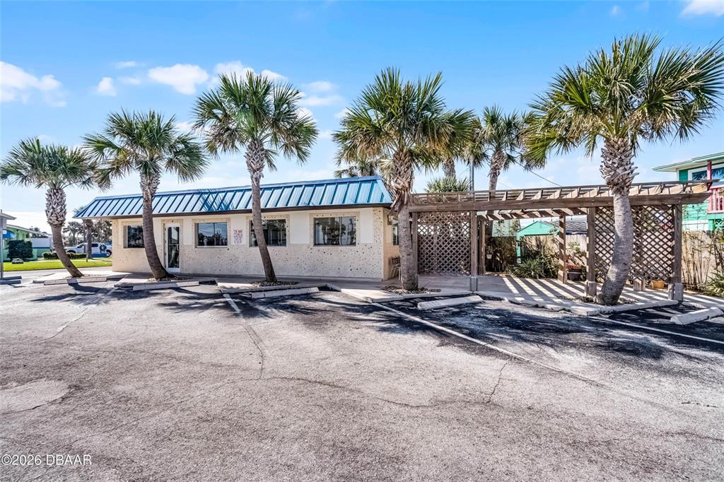 A single-story building with a blue metal roof and a wooden pergola over parking — 819 SR A1A HIGHWAY, NEW SMYRNA BEACH, FL