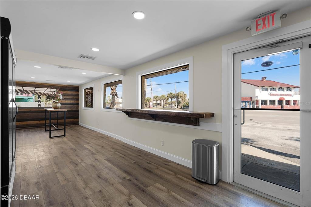 A commercial space features wood-look flooring, a live-edge window bar, and a glass exit door — 819 SR A1A HIGHWAY, NEW SMYRNA BEACH, FL