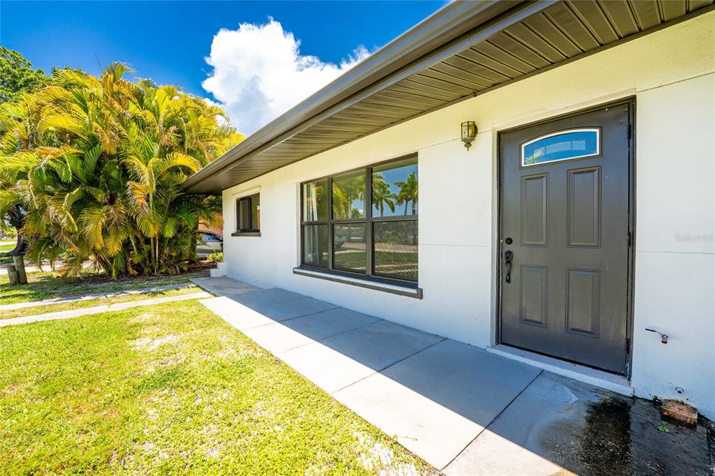 A white house exterior features a dark front door, large windows, and a concrete walkway — 410 W GRACE STREET, PUNTA GORDA, FL