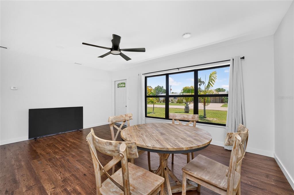 A dining area features a round wooden table, four chairs, and a large window — 410 W GRACE STREET, PUNTA GORDA, FL