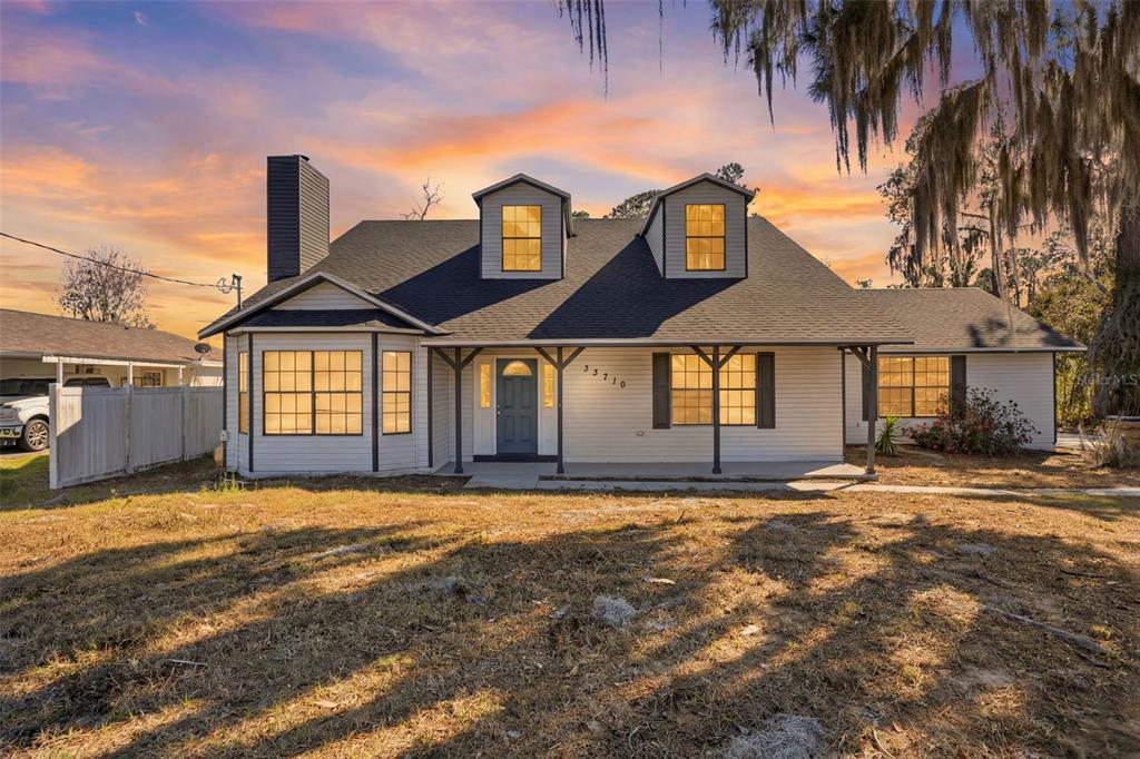 A white house with a dark roof, two dormer windows, and a front porch — 33710 LINDA LANE, LEESBURG, FL