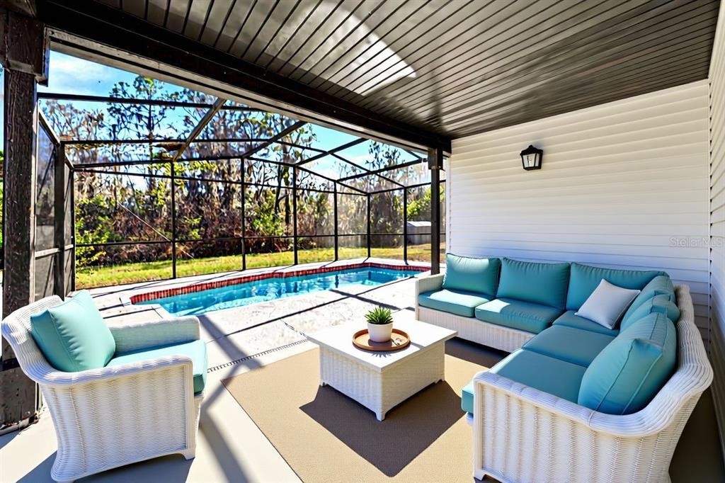 A covered patio features a swimming pool, white wicker furniture, and a teal sectional sofa — 33710 LINDA LANE, LEESBURG, FL