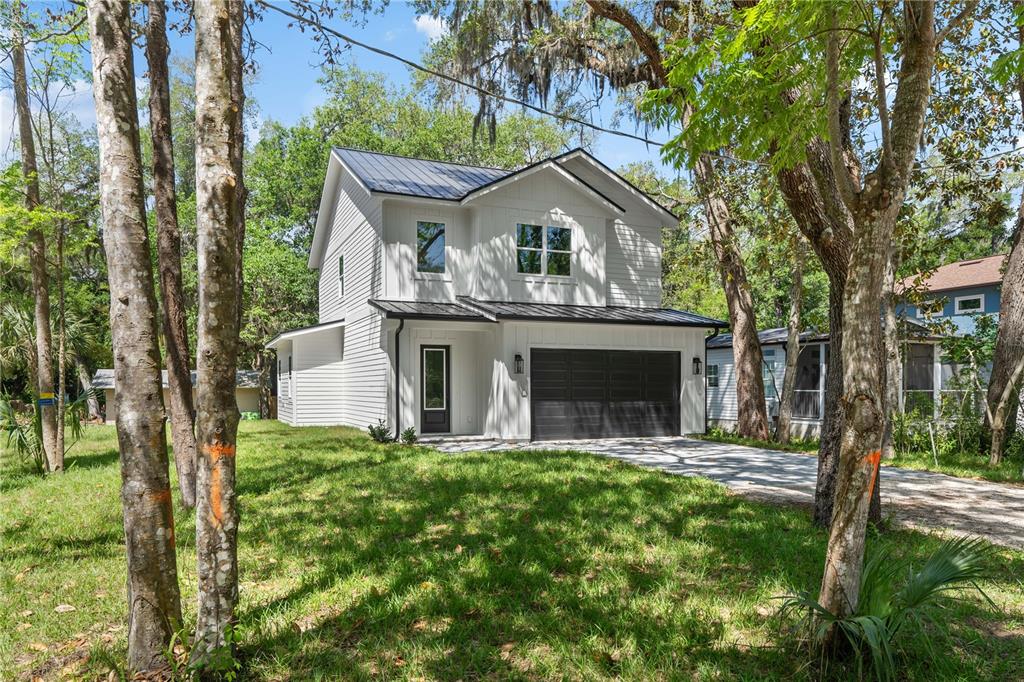 A two-story white house with a black metal roof and a dark garage door — 2 SANCHEZ AVENUE, PALM COAST, FL