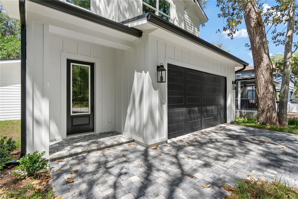 A white house exterior features a black garage door, a matching front door, and pavers — 2 SANCHEZ AVENUE, PALM COAST, FL