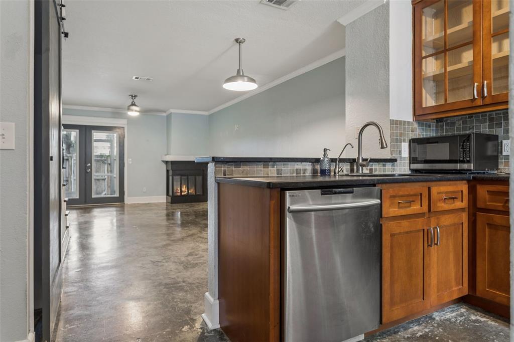 A kitchen with wood cabinets and stainless steel appliances overlooks a living area with concrete floors — 5720 DALDEN DRIVE UNIT 5720, TAMPA, FL