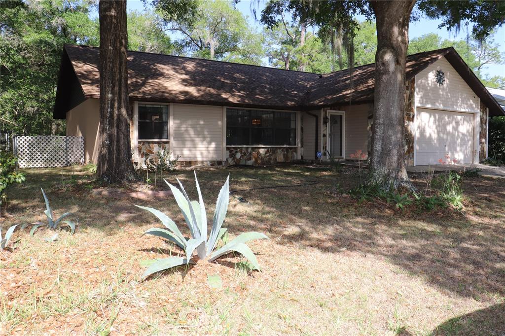 A single-story house with a brown roof, stone accents, and a front-facing garage — 1112 NE 130 TERRACE, SILVER SPRINGS, FL