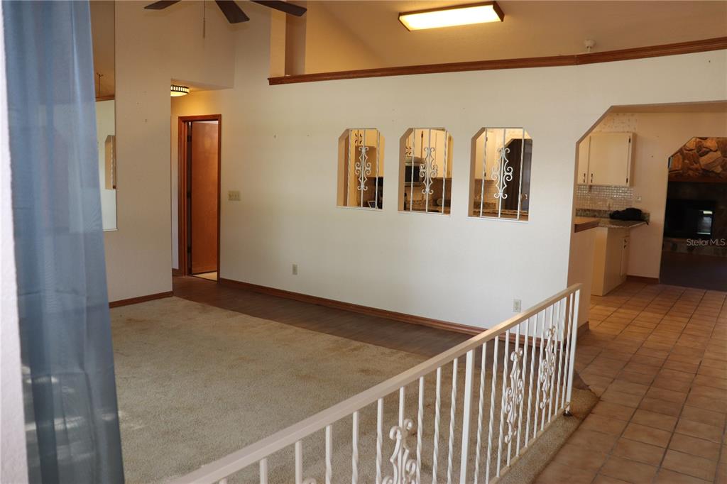 A living room with carpeted flooring, a white metal railing, and decorative wall cutouts — 1112 NE 130 TERRACE, SILVER SPRINGS, FL