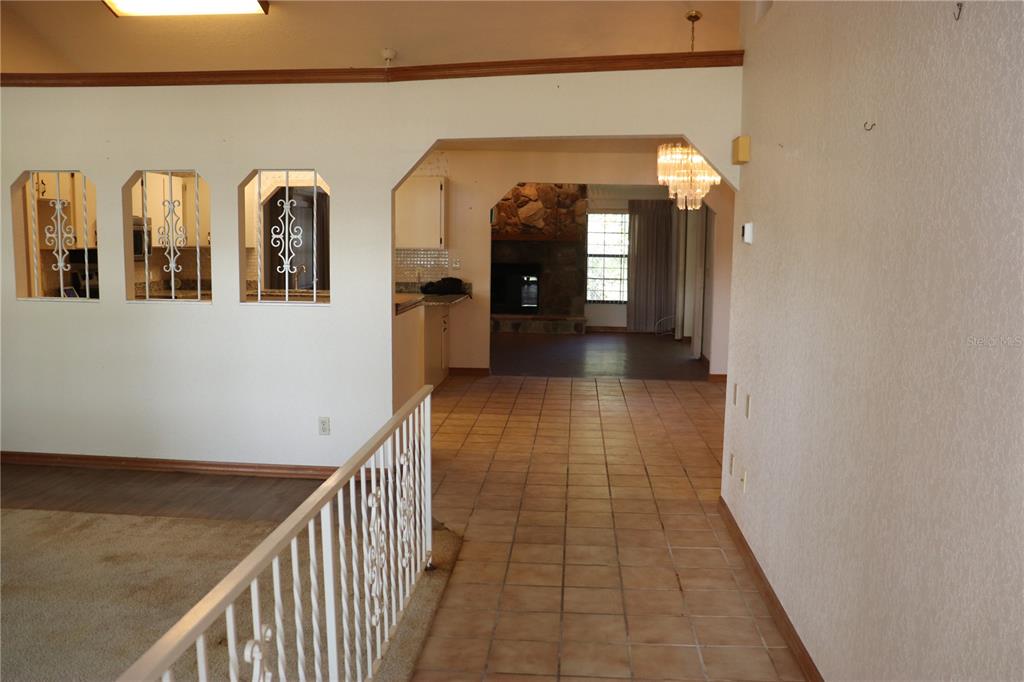 An interior view shows a tiled hallway leading to a living area with a stone fireplace — 1112 NE 130 TERRACE, SILVER SPRINGS, FL