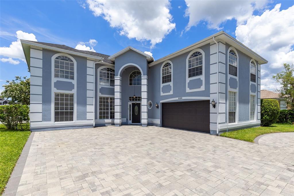 A two-story blue house with white trim and a paved driveway under a cloudy sky — 224 HAMMOCK DUNES PLACE, ORLANDO, FL