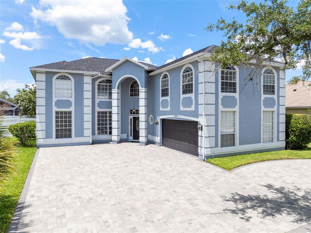 A two-story blue house with white trim and a paved driveway under a blue sky — 224 HAMMOCK DUNES PLACE, ORLANDO, FL