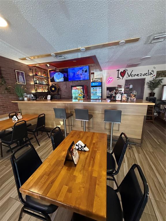 A restaurant interior features a wooden bar, tables with black chairs, and a brick wall — 36657 US HIGHWAY 19 N, PALM HARBOR, FL