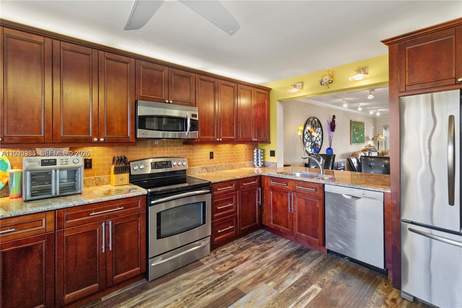 A kitchen with dark wood cabinets, stainless steel appliances, and granite countertops — 5519 FAIRWAY PARK DR # 203, Boynton Beach FL 33437, BOYNTON BEACH, FL
