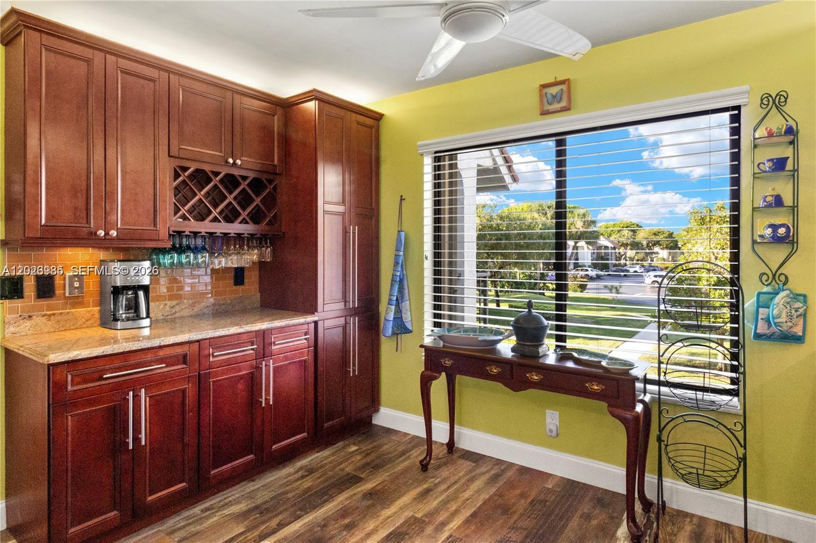 A kitchen area features dark wood cabinetry, a wine rack, and a window with blinds — 5519 FAIRWAY PARK DR # 203, Boynton Beach FL 33437, BOYNTON BEACH, FL