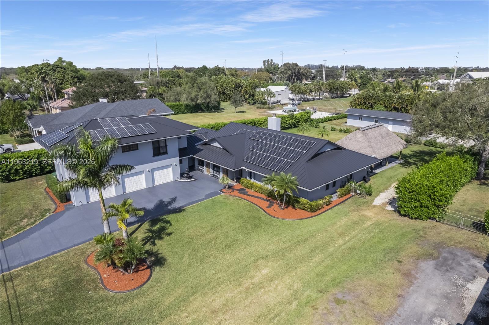 An aerial view shows a two-story house with solar panels and a detached tiki hut — 14651 SW 16th St, Davie FL 33325, DAVIE, FL