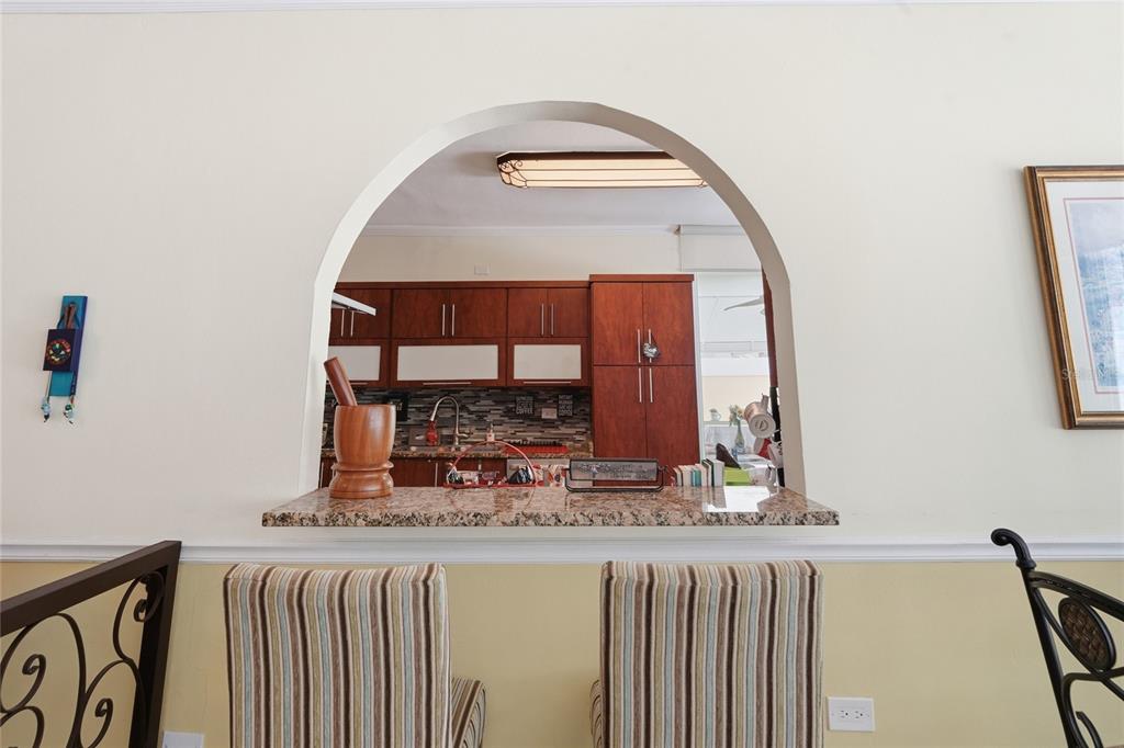 A view through an arched opening into a kitchen with wood cabinets and granite counters — 644 HELICONIA, SAN JUAN, PR