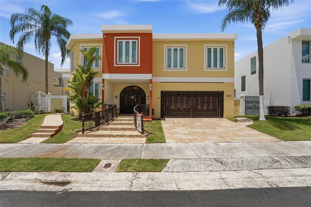 A two-story house with a yellow and orange facade, arched entrance, and a double garage — 644 HELICONIA, SAN JUAN, PR