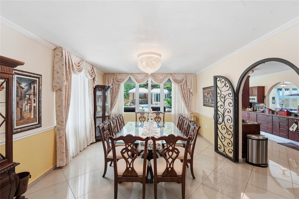 A formal dining room features a glass-topped table, ornate wooden chairs, and a crystal chandelier — 644 HELICONIA, SAN JUAN, PR