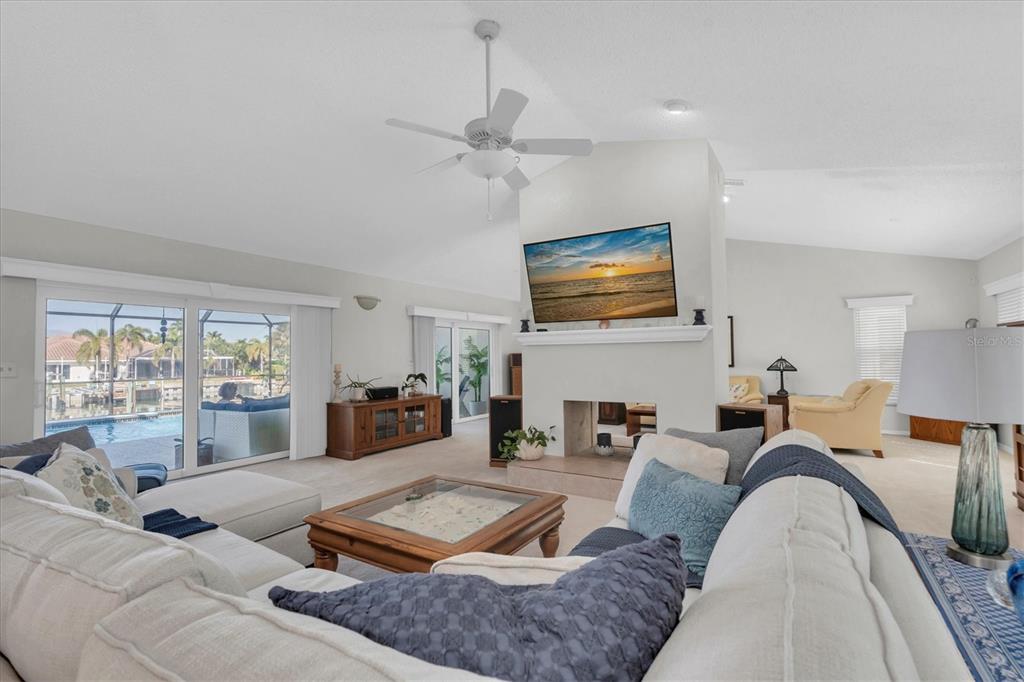 A living room features a sectional sofa, a fireplace with a mounted television, and pool views — 4961 61ST AVENUE S, ST PETERSBURG, FL