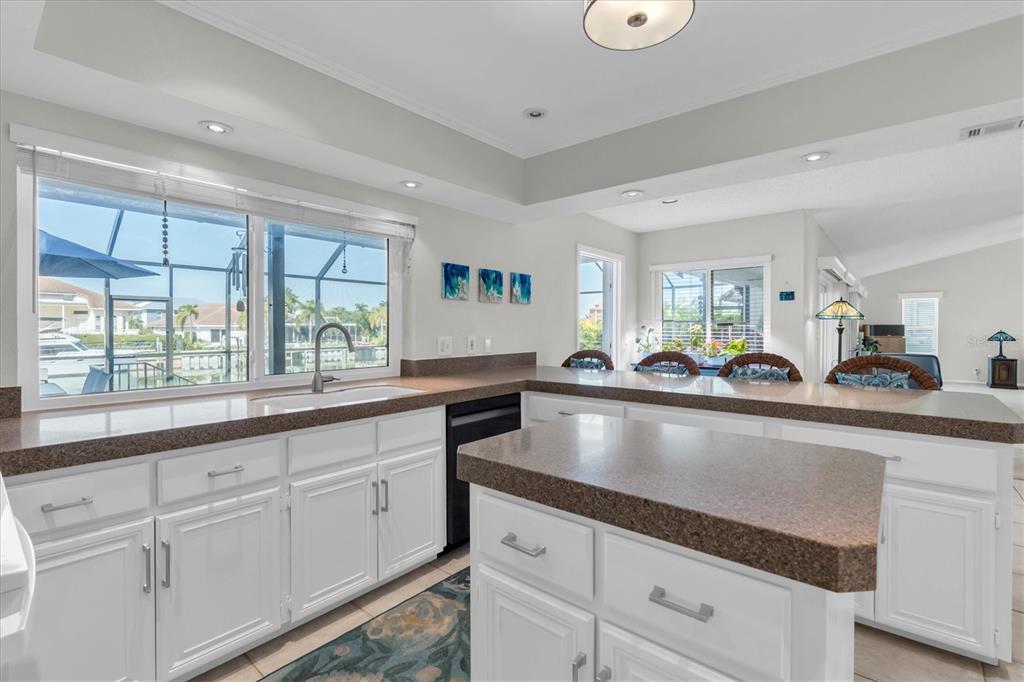 A kitchen features white cabinets, brown countertops, a central island, and a large window view — 4961 61ST AVENUE S, ST PETERSBURG, FL