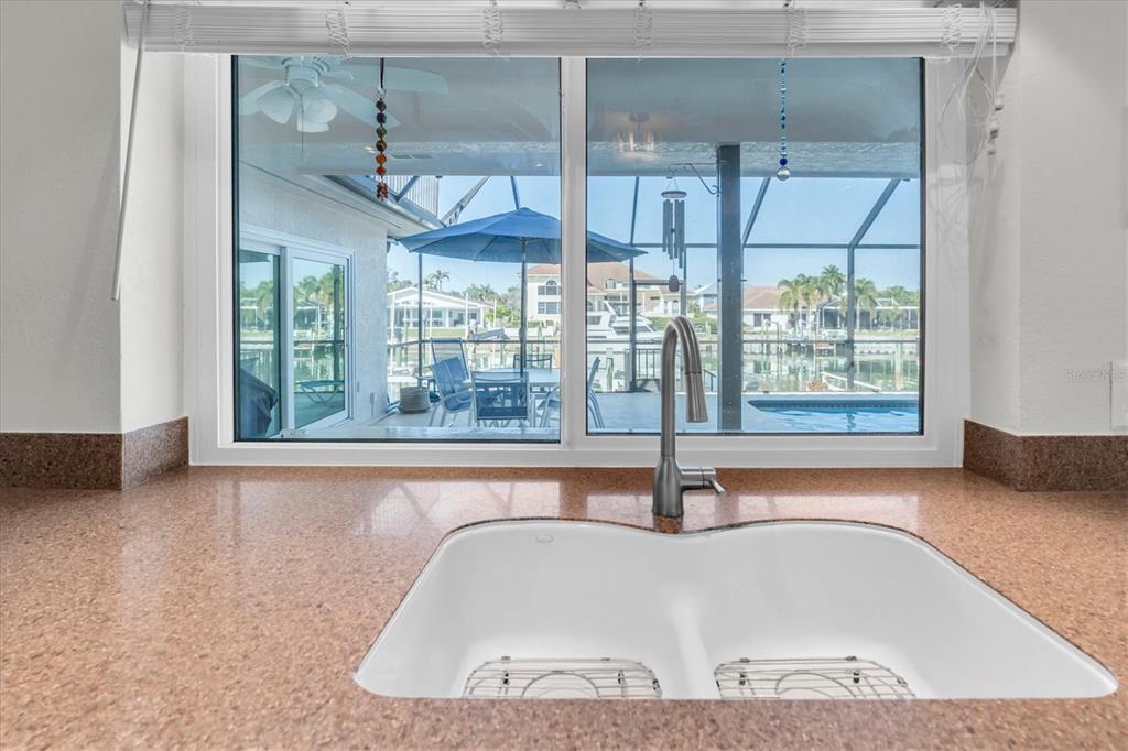 A kitchen sink with a view of a patio, pool, and canal through a window — 4961 61ST AVENUE S, ST PETERSBURG, FL