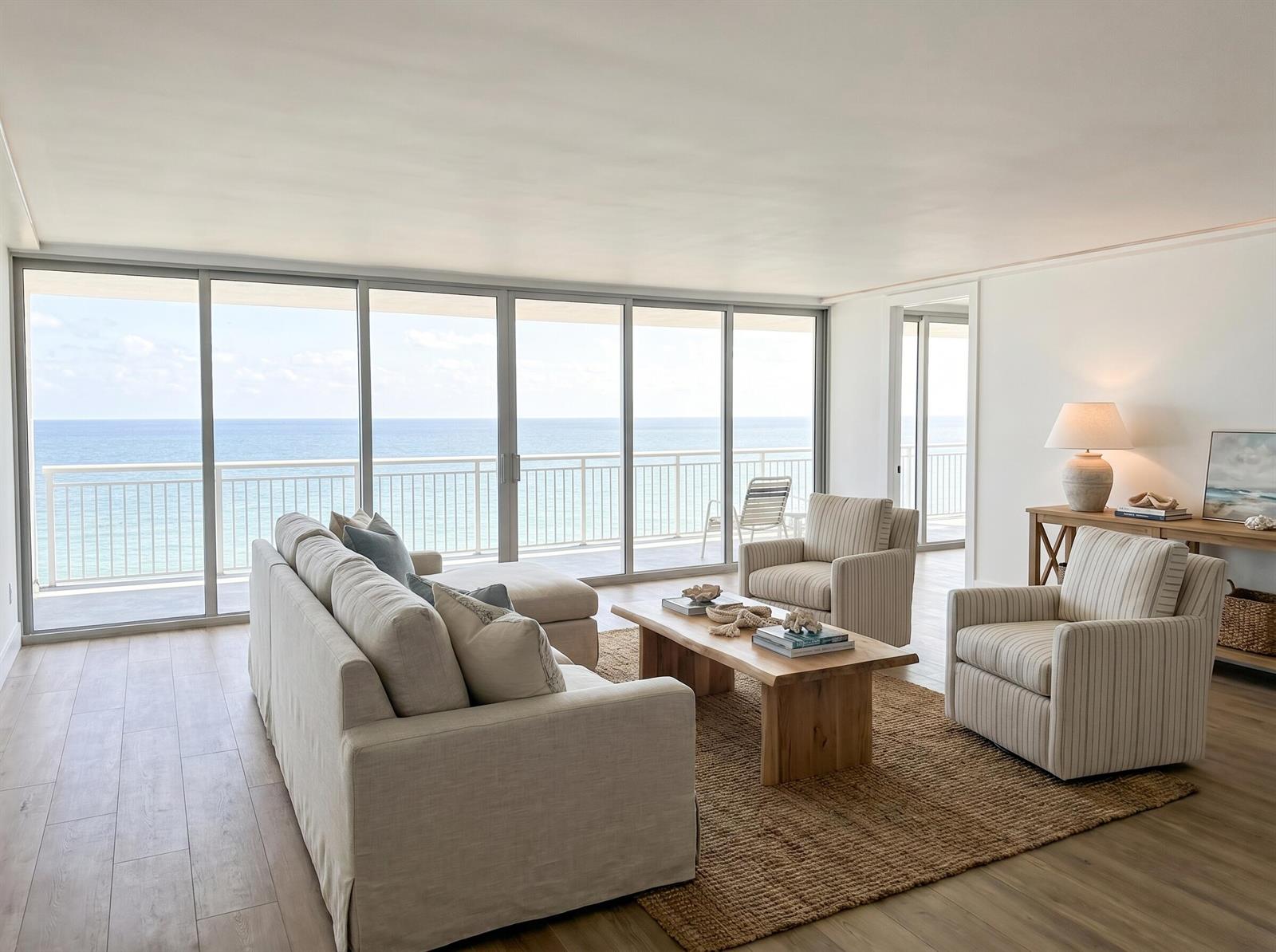 A living room features a beige sofa, striped armchairs, and floor-to-ceiling windows overlooking the ocean — 1390 S Ocean Boulevard # f, Pompano Beach FL 33062, POMPANO BEACH, FL