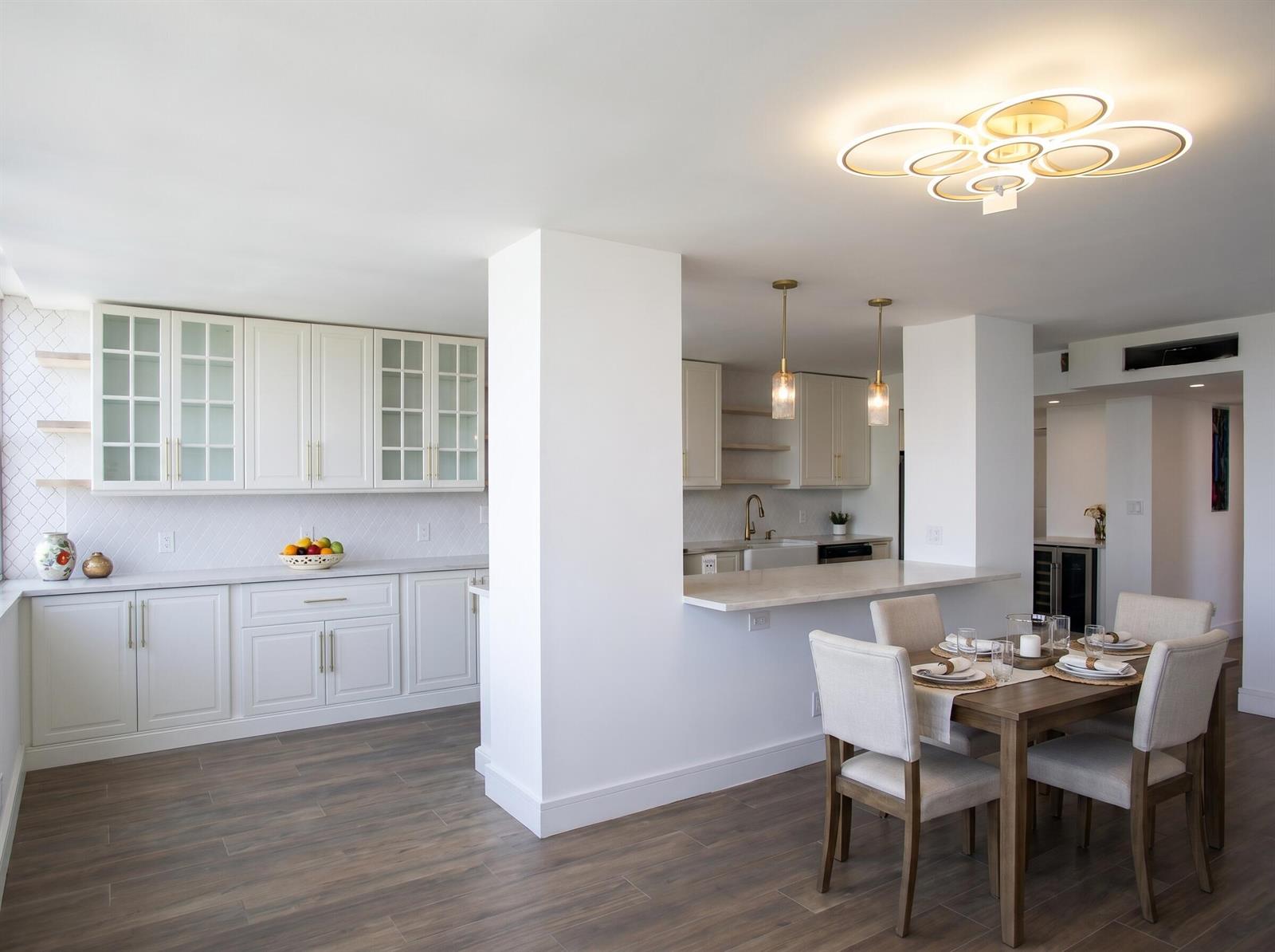 A kitchen and dining area with white cabinetry, wood-look flooring, and a modern ceiling light — 1390 S Ocean Boulevard # f, Pompano Beach FL 33062, POMPANO BEACH, FL