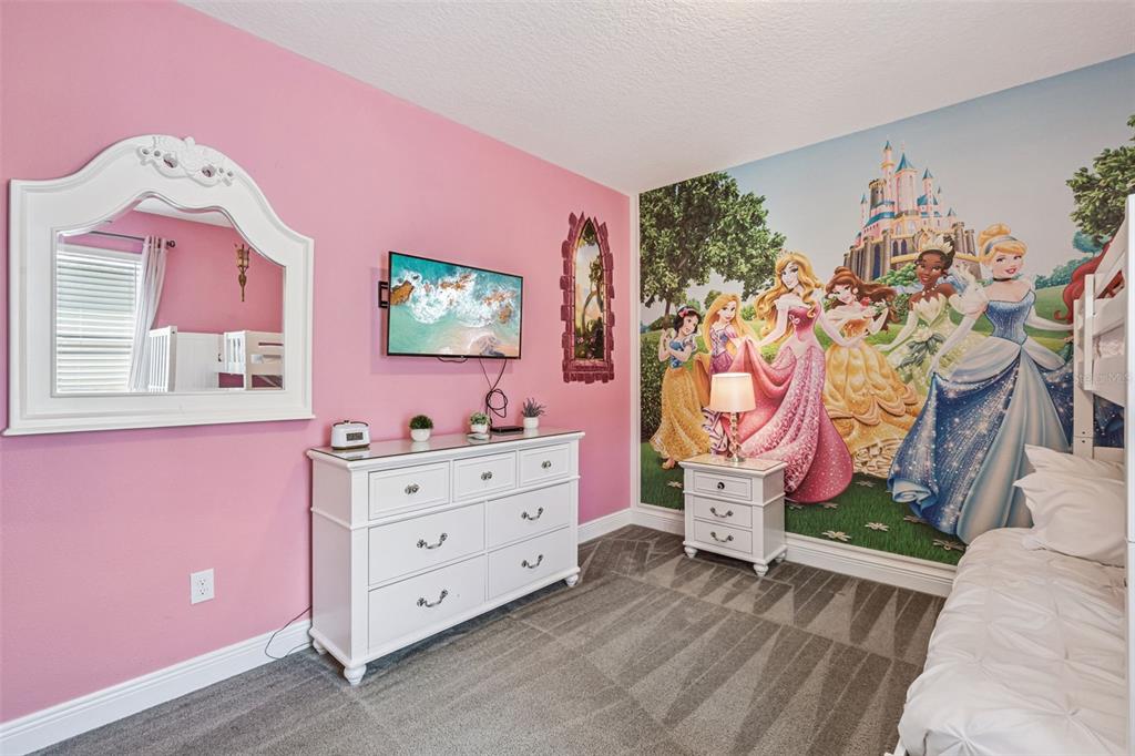 A bedroom with pink walls, a Disney princess mural, white furniture, and gray carpeting — 7649 FAIRFAX DRIVE, KISSIMMEE, FL