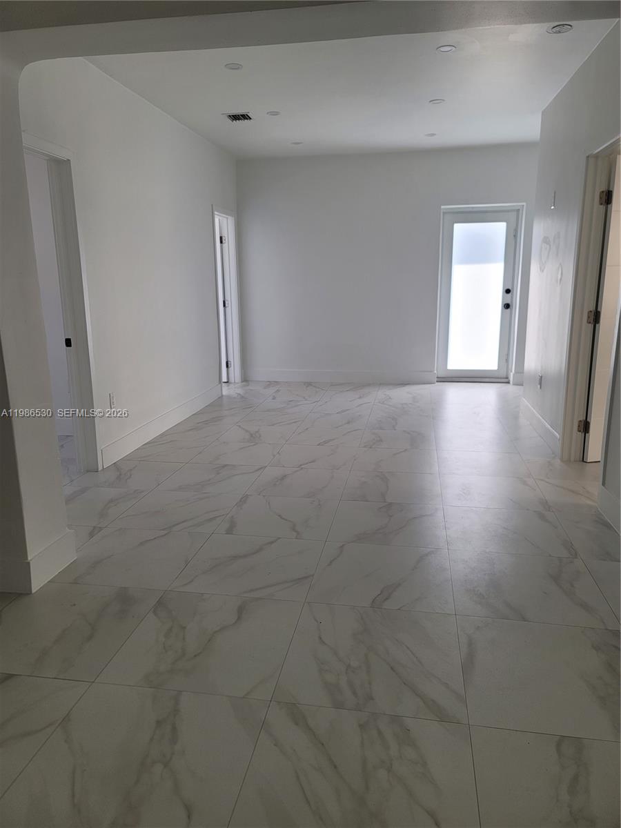 An interior room features white walls, recessed lighting, and large white marble-patterned floor tiles — 1975 NW 24th Ct, Miami FL 33125, MIAMI, FL