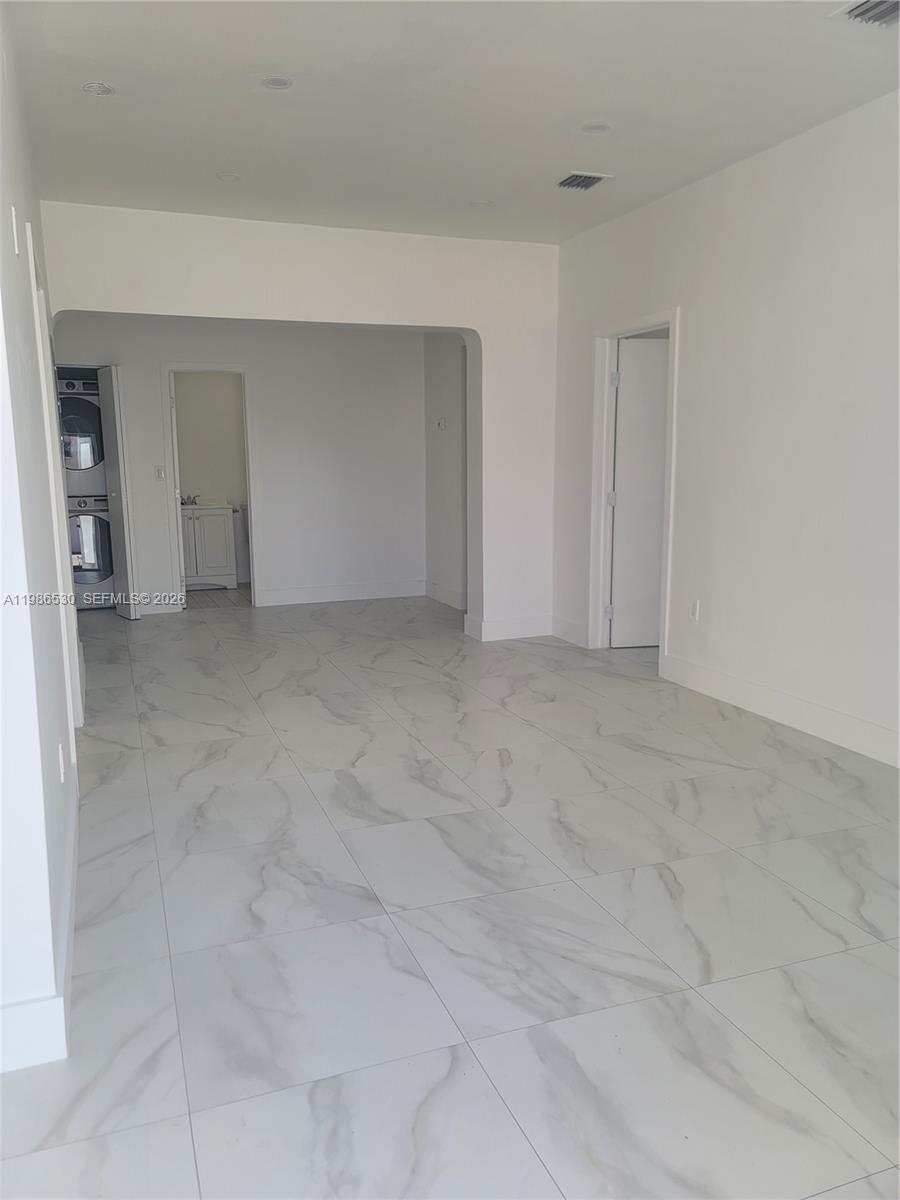 A bright, empty room features white walls, large marble-patterned floor tiles, and a laundry closet — 1975 NW 24th Ct, Miami FL 33125, MIAMI, FL