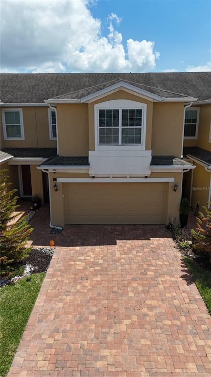 An exterior view of a two-story townhouse with a beige facade and brick paver driveway — 1205 TETON DRIVE, KISSIMMEE, FL