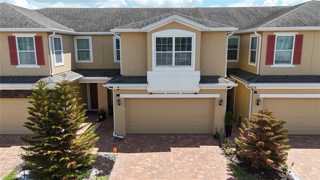 An exterior view of a two-story townhouse with a beige stucco facade and brick driveway — 1205 TETON DRIVE, KISSIMMEE, FL