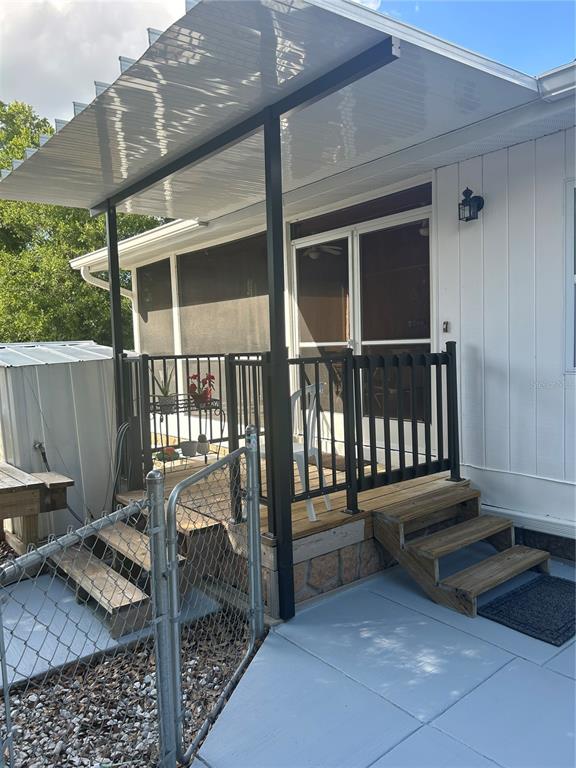 A wooden deck with black railings and a covered porch sits beside a white house — 5522 SWAYING PALM, PUNTA GORDA, FL