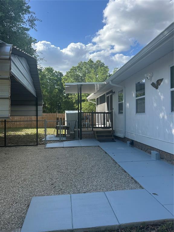 A gravel yard leads to a painted concrete walkway and a covered porch with stairs — 5522 SWAYING PALM, PUNTA GORDA, FL