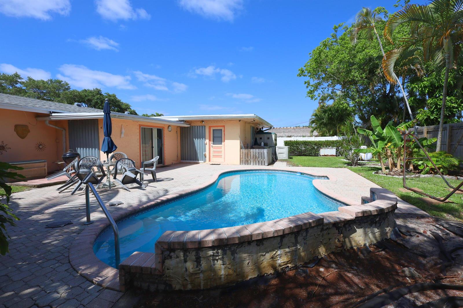 A backyard features a swimming pool with a brick-walled edge and a paved patio area — 1259 SW 7th Street, Boca Raton FL 33486, BOCA RATON, FL