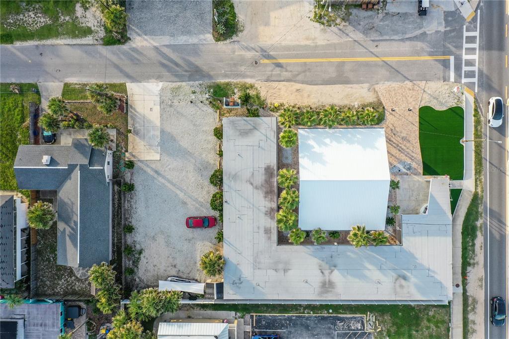 An aerial view shows a building with a white roof, surrounding palm trees, and parking — 111 S 12TH STREET, FLAGLER BEACH, FL