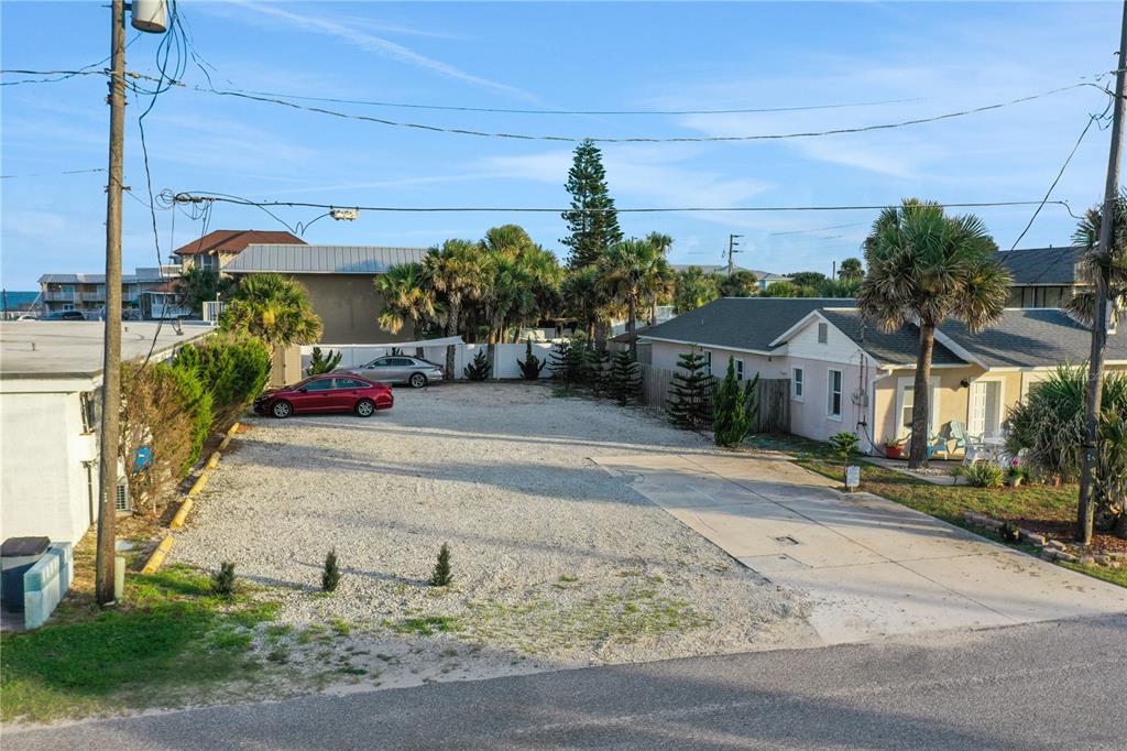 A gravel parking lot sits between two residential buildings under a clear blue sky — 111 S 12TH STREET, FLAGLER BEACH, FL
