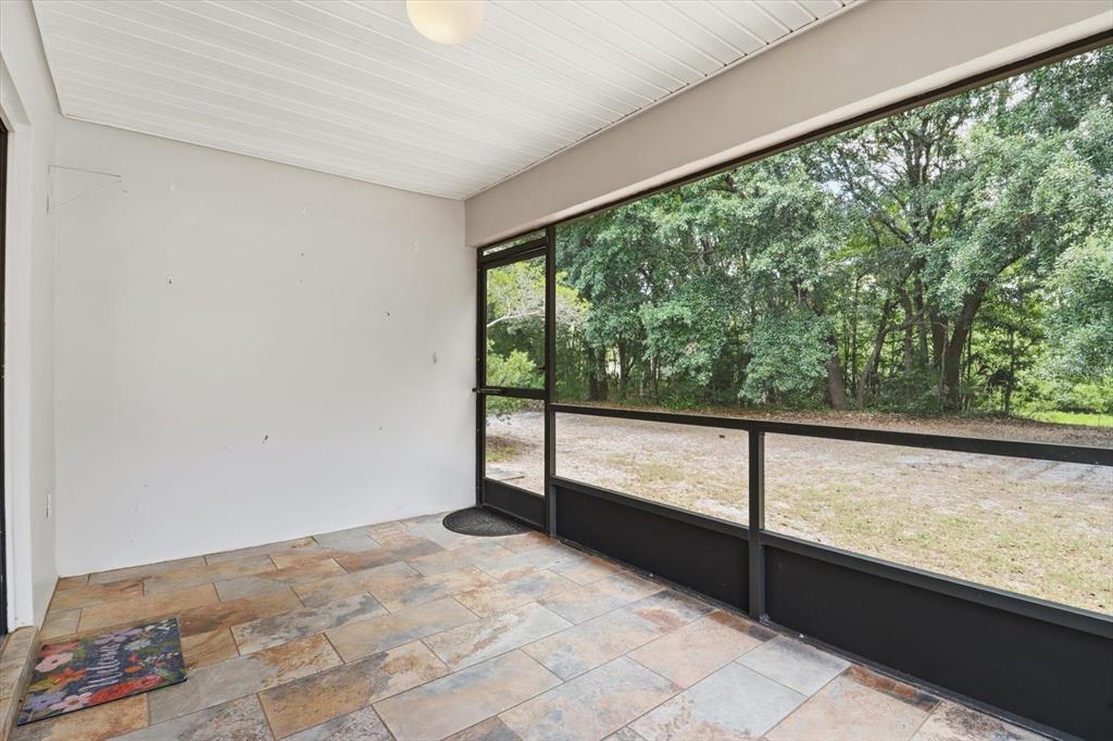 A screened-in porch features tiled flooring, a white ceiling, and a view of trees — 54 JAMAICA STREET, HOMOSASSA, FL