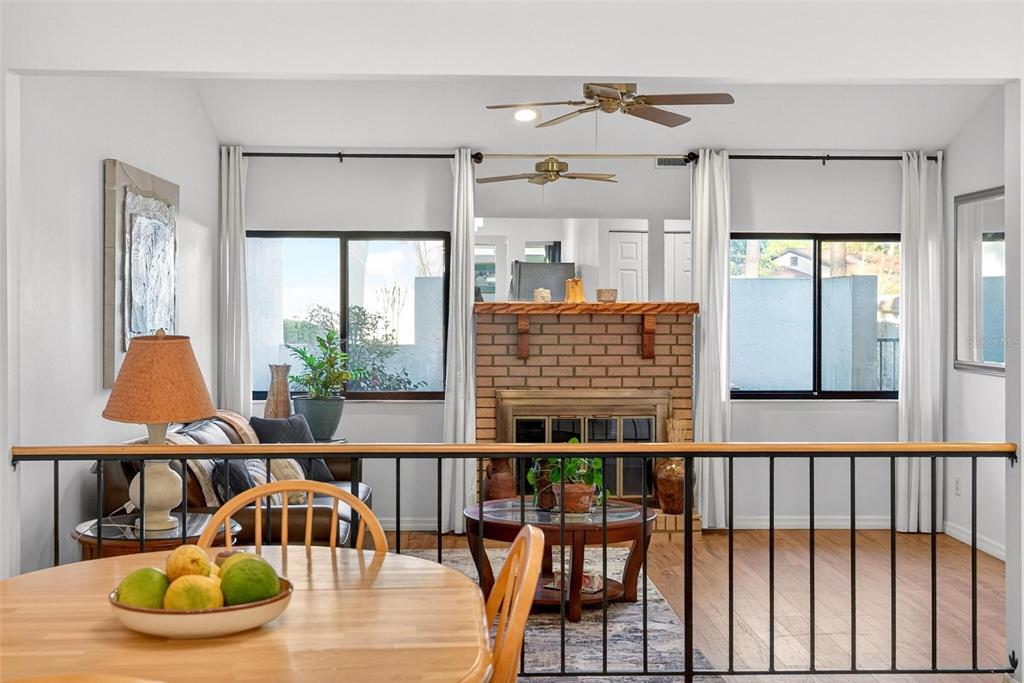 A dining area overlooks a sunken living room featuring a brick fireplace and large windows — 3804 NE 17TH STREET, OCALA, FL