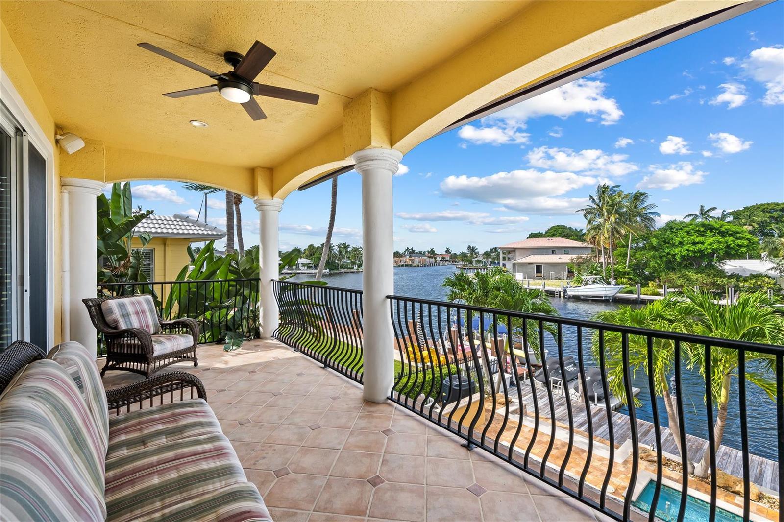 A covered balcony with tile flooring, wicker furniture, and a view of a canal — 2637 NE 28th Court, Lighthouse Point FL 33064, LIGHTHOUSE POINT, FL