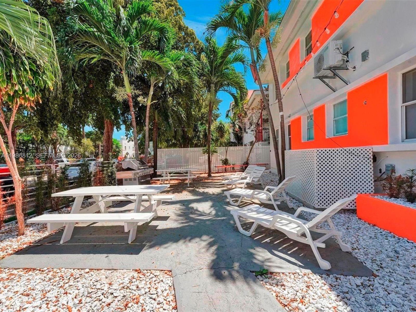 An outdoor patio area features white picnic tables, lounge chairs, and bright orange exterior walls — 1000 7th St # 10, Miami Beach FL 33139, MIAMI BEACH, FL