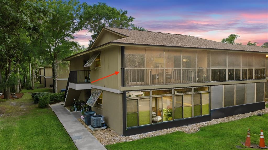 An exterior view of a two-story building featuring a screened-in balcony and lower patio — 140 ORCHID WOODS COURT UNIT 13B, DELTONA, FL