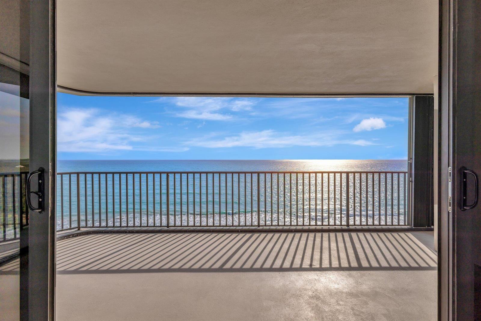 A balcony with a metal railing overlooks the ocean under a bright blue sky — FORT PIERCE, FL
