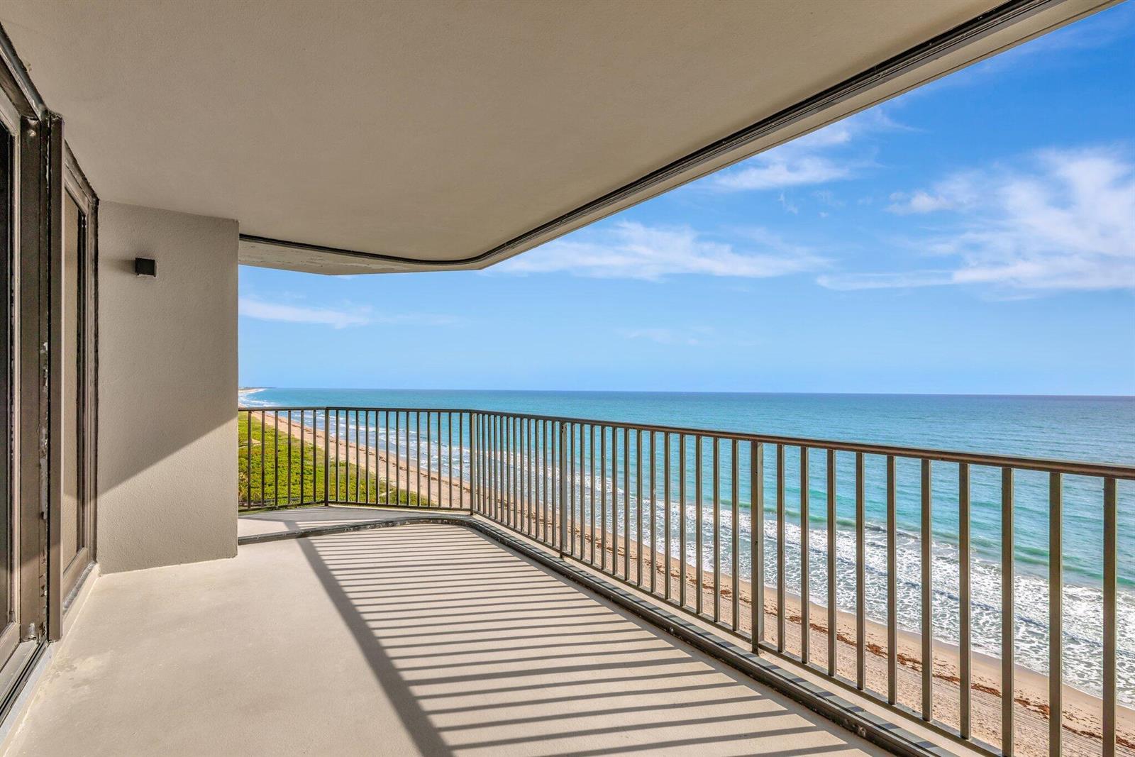 A balcony with a metal railing overlooks a sandy beach and the ocean — FORT PIERCE, FL