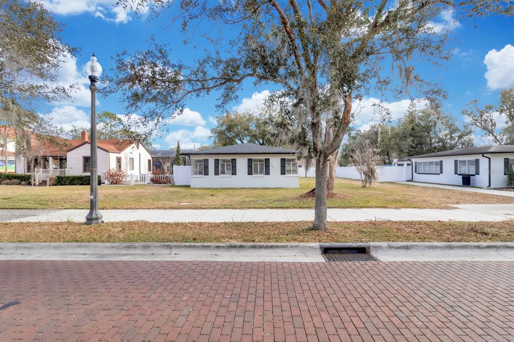 A street view shows a white house with black shutters behind a brick road — 307 E MONUMENT AVENUE UNIT A, KISSIMMEE, FL