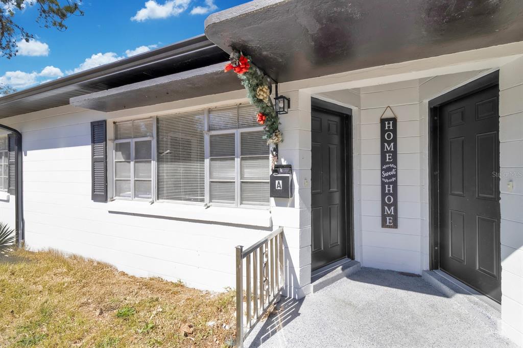 The exterior of a white building features two black doors and a window with shutters — 307 E MONUMENT AVENUE UNIT A, KISSIMMEE, FL
