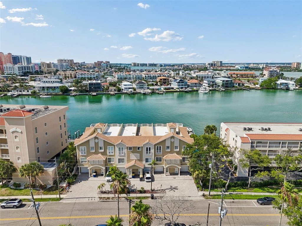 An aerial view shows a multi-unit townhouse complex situated along a waterfront canal — 620 BAYWAY BOULEVARD UNIT 5, CLEARWATER BEACH, FL