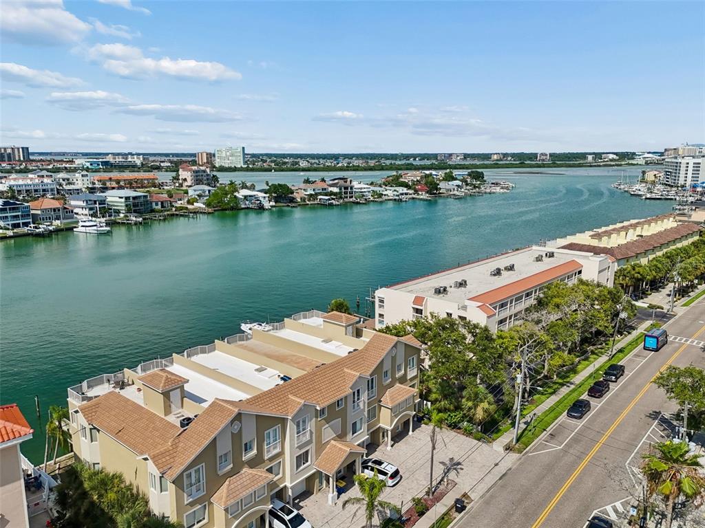 An aerial view shows waterfront townhomes with tan siding and brown roofs along a road — 620 BAYWAY BOULEVARD UNIT 5, CLEARWATER BEACH, FL