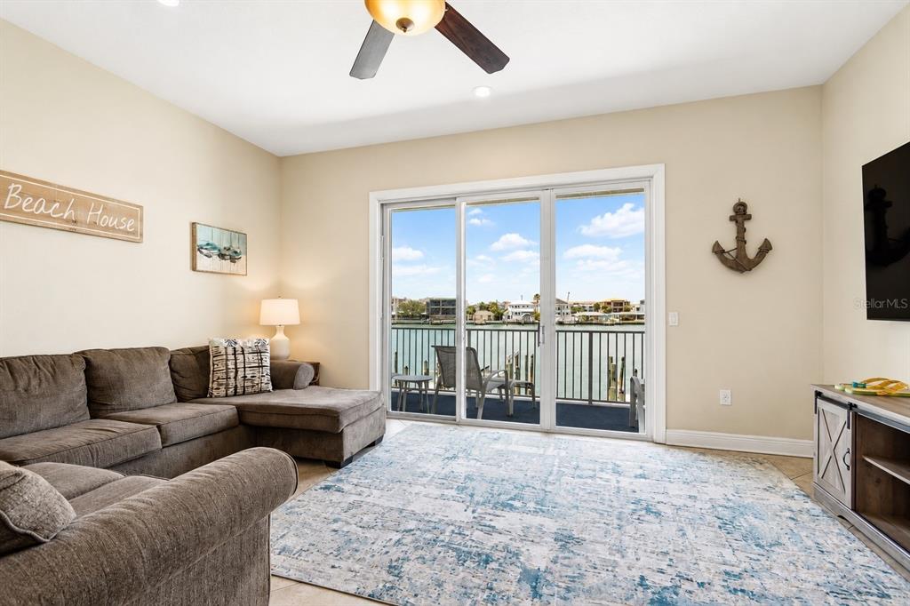 A three-story townhouse exterior features tan stucco walls, multiple balconies, and several ground-level garage doors — 620 BAYWAY BOULEVARD UNIT 5, CLEARWATER BEACH, FL