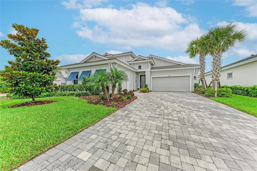 A single-story house with a paved driveway, a two-car garage, and a landscaped front yard — 17725 ROOST PLACE, LAKEWOOD RANCH, FL