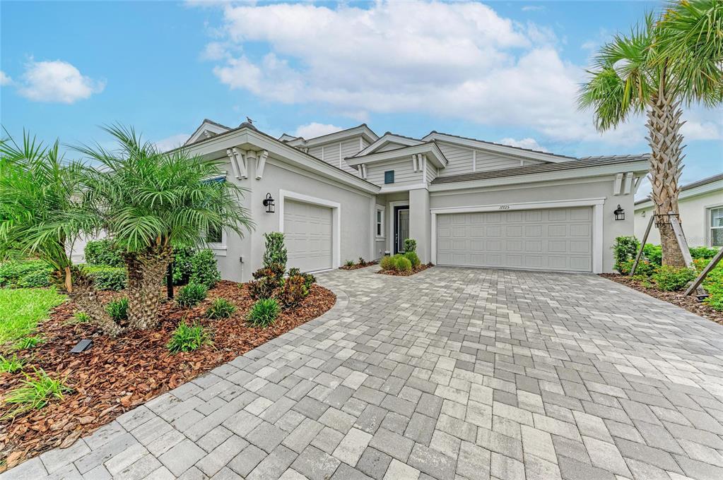 A single-story house with a gray exterior, two garage doors, and a paved driveway — 17725 ROOST PLACE, LAKEWOOD RANCH, FL